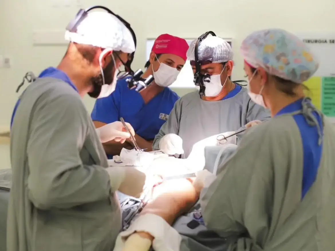 Cirurgiões e auxiliares com toucas, máscaras e aventais cirúrgicos